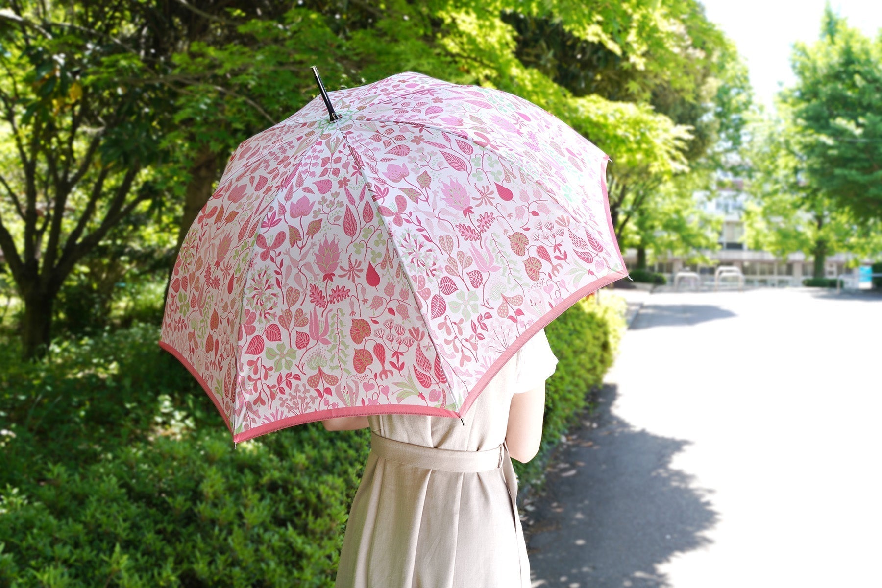ピンク色の植物柄のレディース傘を差す女性
