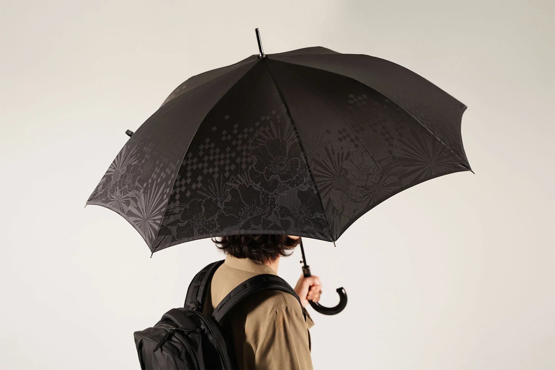ブラックカラーの晴雨兼用メンズ傘を差す男性