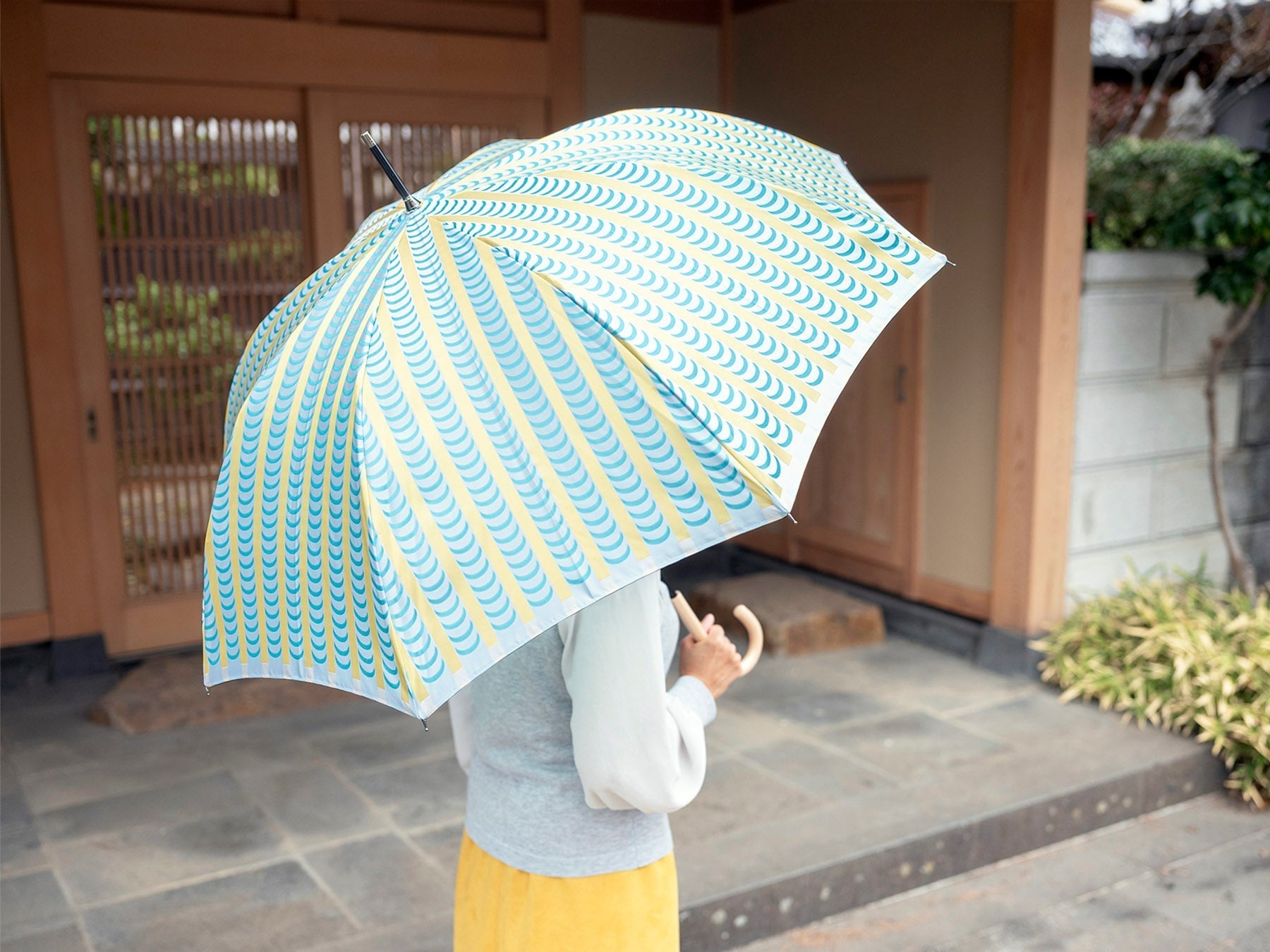 グリーンとイエローの晴雨兼用傘を差す女性